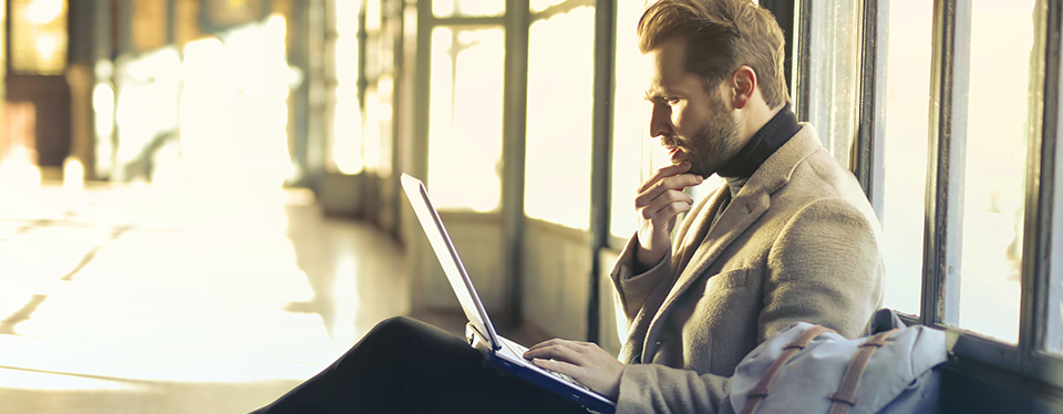 Photo of a man sat working on his laptop in an airport lounge