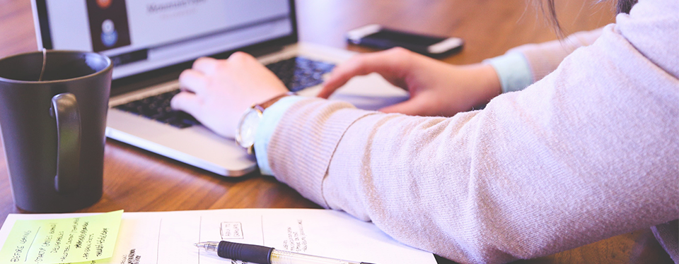 Cropped photo of a person working on their laptop at home.